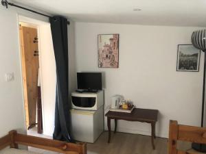 a living room with a television and a table with a table sidx sidx at Chambre d'hôtes La Cavaille in Veyrines-de-Vergt
