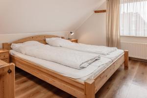 a bedroom with a wooden bed with white sheets at 50188Ferienwohnung Windspiel in Harlesiel