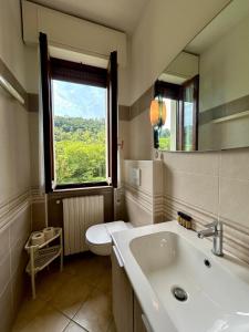 a bathroom with a sink and a toilet and a window at Kibilu - Cittiglio vicinanze Ospedale, Lago Maggiore in Cittiglio