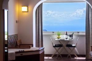 a room with a table and a large window with a table and chairs at La Moresca in Ravello