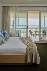 a bedroom with a bed and a balcony with a table at Hotel Slipway in Dar es Salaam