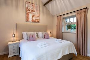 a bedroom with a large white bed with pink pillows at Beach Tree House in Gloucestershire