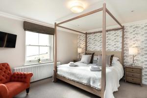 a bedroom with a canopy bed and a chair at Beach Tree House in Gloucestershire +6 photos