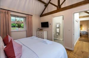 a bedroom with a white bed and a television at Beach Tree House in Gloucestershire