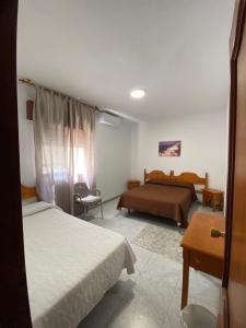 a hotel room with two beds and a table at Hotel Mu&ntilde;oz in Motril