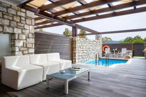 a living room with a white couch and a pool at Princess Resort, Santikos Collection in Agia Paraskevi