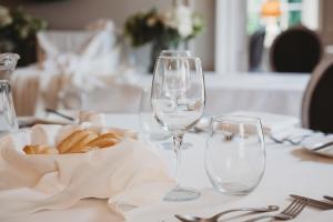 a table with two wine glasses and a basket of bread at Greenwoods Hotel & Spa in Stock