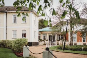 a large white house with a cobblestone yard at Greenwoods Hotel & Spa in Stock