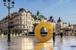 a man standing in front of a gold sign in a city at Le petit meublé hyper Centre in Orléans