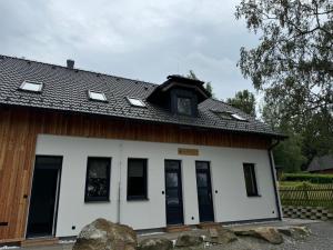 a white house with a black roof at Apartmány Rak Jestřábí in Černá v Pošumaví