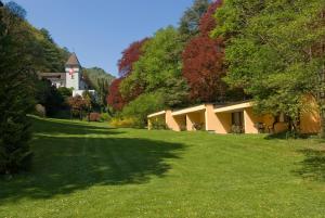 ein Haus inmitten eines grünen Feldes mit Bäumen in der Unterkunft Hotel Schloss Ragaz in Bad Ragaz