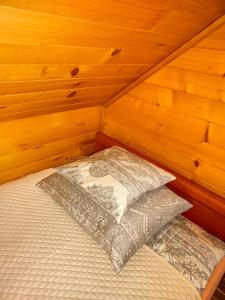 a bed with a pillow in a room with wooden walls at Nowoczesny Domek Góralski in Kielce