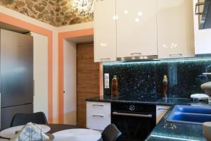 a kitchen with white cabinets and a black counter top at Φιλόξενο Σπίτι in Nafplio