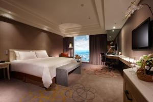 um quarto com uma cama, uma secretária e uma televisão em Hotel Royal Hsinchu em Cidade de Hsinchu