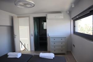 a bedroom with two towels on two beds and a window at Golden Sand Suites 2 in Anavyssos