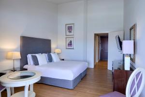 a bedroom with a bed and a table and a tv at Princess Resort, Santikos Collection in Agia Paraskevi