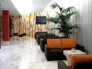 a living room with couches and a palm tree at Hotel Habitat in Giussano