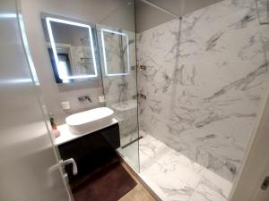 a bathroom with a sink and a glass shower at Black Sea Luxury Apartament - Mamaia Nord Beachfront in Mamaia Nord