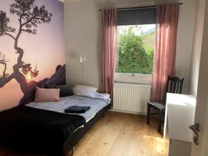 a bedroom with a bed with a tree mural on the wall at Trevlig villa, centralt i Visby in Visby