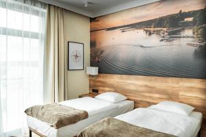two beds in a room with a painting on the wall at Marina Sława in Sława +61 photos