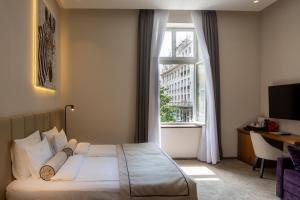 a bedroom with a bed and a desk and a window at Maison Royale in Belgrade