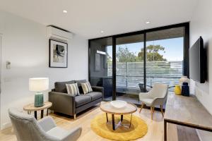 sala de estar con sofá, mesa y sillas en Camberwell Serviced Apartments en Melbourne