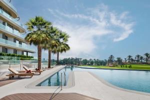 a swimming pool with palm trees next to a building at JA Lake View Hotel, Dubai in Dubai