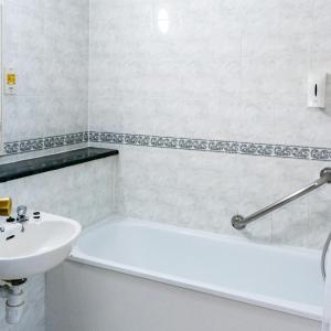 a bathroom with a white tub and a sink at Carrington House Hotel in Bournemouth