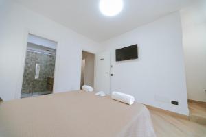 a white bedroom with a bed and a tv on the wall at Guest Room 144 in San Giovanni in Fiore