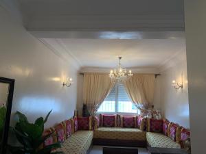 a living room with a couch and a chandelier at Résidence Martil Deluxe in Martil