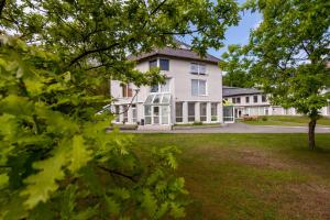 a large white house with trees in front of it at Prie Ąžuolo in Juodkrantė