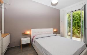 ein weißes Schlafzimmer mit einem Bett und einem Fenster in der Unterkunft Cozy Home In Marina Di Ragusa With Wifi in Marina di Ragusa