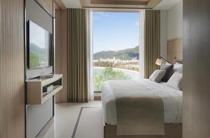 a hotel room with a bed and a large window at Amari Phuket in Patong Beach