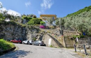 a house on a hill with cars parked on a street at Cozy Home In Sori With House Sea View in Sori