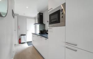 a kitchen with white cabinets and a tv on the wall at 2 Bedroom Nice Home In Hellendoorn in Hellendoorn +9 photos