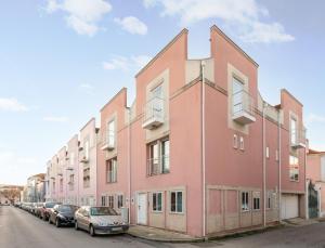 a pink building with cars parked in a parking lot at BeSmart Suites with Private WC by Home Sweet Home Aveiro in Aveiro