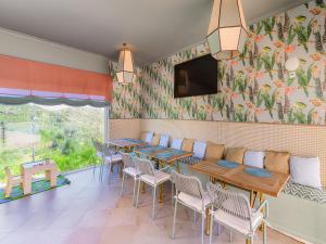 a restaurant with tables and chairs and a tv on the wall at NAU Salema Beach Village in Salema