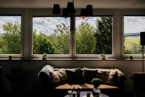 a couch sitting in a room with three windows at Ferienwohnung Emma in Güntersberge