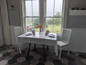 a white table with two chairs and a vase of flowers at East Ferry Bed and Breakfast in Brier and Long Islands +17 photos
