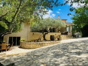 ein Haus mit einem Baum und einer Steinauffahrt in der Unterkunft Magnifique Villa typique du Sud avec Piscine privée et jardin méditerranéen in Saint-Vincent-de-Barbeyrargues