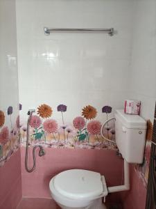 a bathroom with a toilet and flowers on the wall at VIDYA Homestay in Hampi