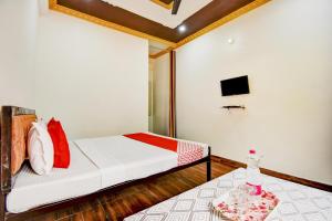 a bedroom with a bed and a tv on the wall at OYO Pine Tree in Mussoorie