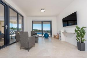 Una sala de estar con paredes y ventanas blancas y una mesa y sillas. en Villa Malusy ZadarVillas, en Rovanjska