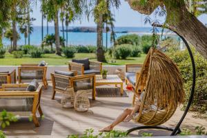 a woman is sitting in a hammock on a patio at Nissi Beach Resort in Ayia Napa