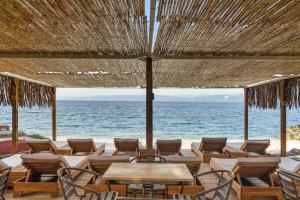 a patio with tables and chairs and the ocean at Anassa Mare Villas & Residences by GHH in Gaios