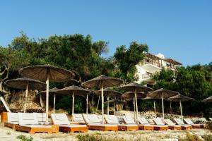 a row of chairs and umbrellas on a beach at Anassa Mare Villas & Residences by GHH in Gaios