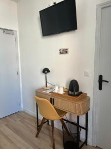 a desk with a chair and a television on a wall at Les Paquebots - Hôtel & Restaurant in Port-Vendres