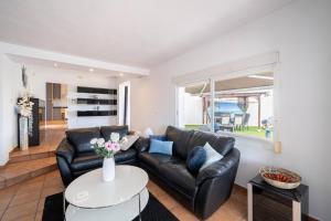 a living room with a black leather couch and a table at Casablanca Spaniahome in L’Alfàs del Pi