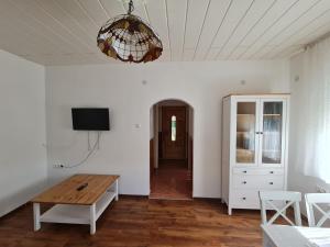 a living room with a wooden table and a chandelier at Zöldház in Balatonmáriafürdő