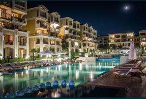 a swimming pool in front of a hotel at night at Студио в Затворен Комплекс Blue in Sozopol